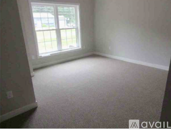 A room with a carpeted floor and a window.