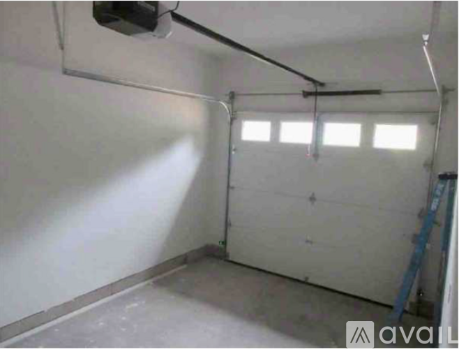 A sparsely furnished garage with a white wall and a window.