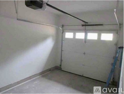 A sparsely furnished garage with a white wall and a window.