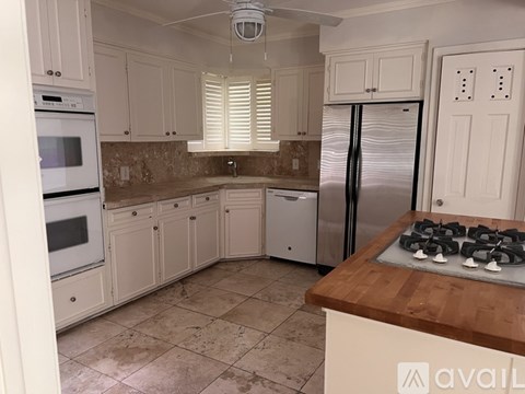 A kitchen with white cabinets and a wooden island.