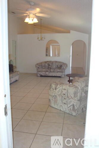 A living room with a couch and a fan.