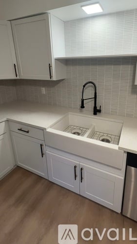 A kitchen with white cabinets and a black faucet.