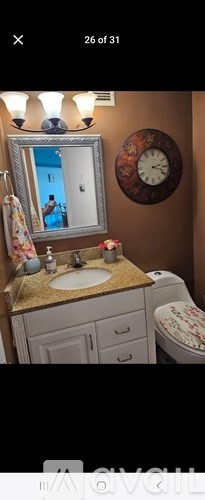 A bathroom with a brown wall and a round clock on it.