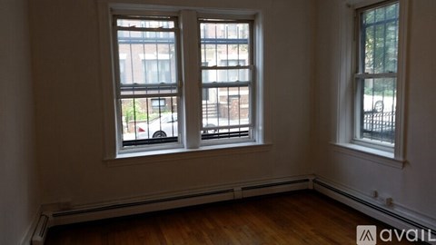 Three windows in a room with wooden floors and white walls.