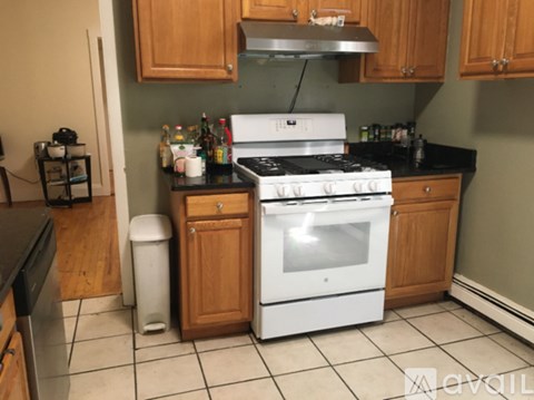 A kitchen with a white stove top oven and black countertops.