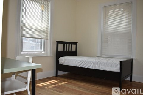 A bedroom with a bed, table and chairs.