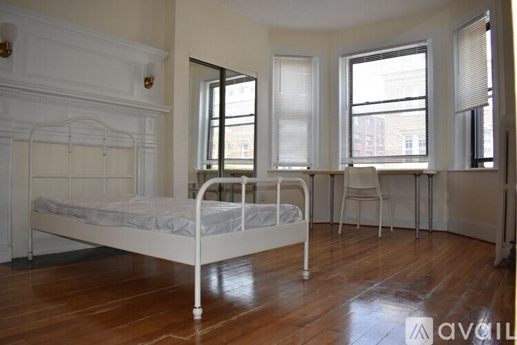 A white metal bed frame in a room with wooden floors and white walls.