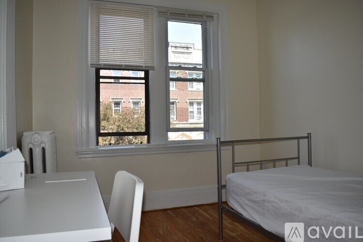 A bedroom with a bed, desk, chair, and window.