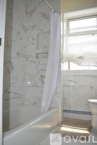 A bathroom with marble walls and a white bathtub.