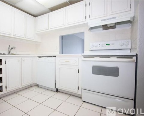 A white kitchen with a stove top oven and a dishwasher.