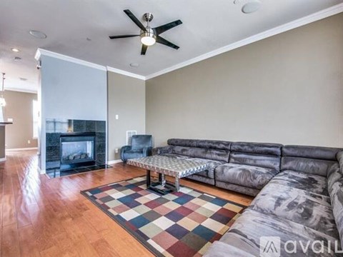 A living room with a grey couch and a checkered rug.