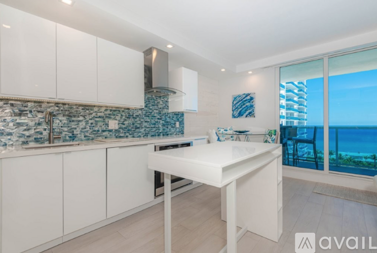 A kitchen with white cabinets and a countertop with a view of the ocean.