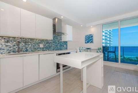 A kitchen with white cabinets and a countertop with a view of the ocean.