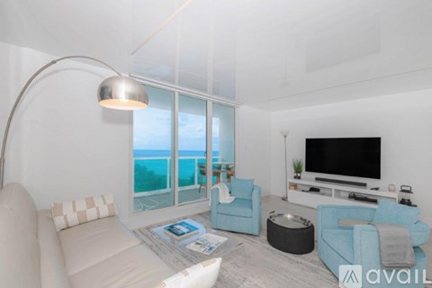A living room with a large window overlooking the beach.