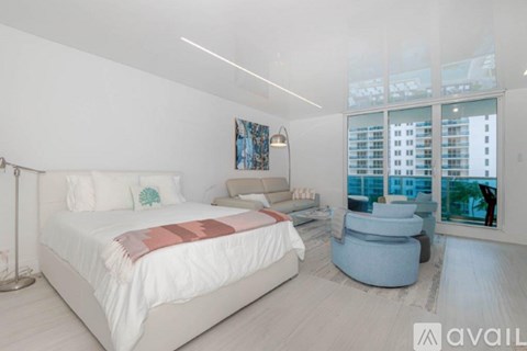 A bedroom with a large bed and a view of a cityscape through the window.