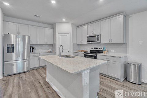 A modern kitchen with white cabinets and stainless steel appliances.