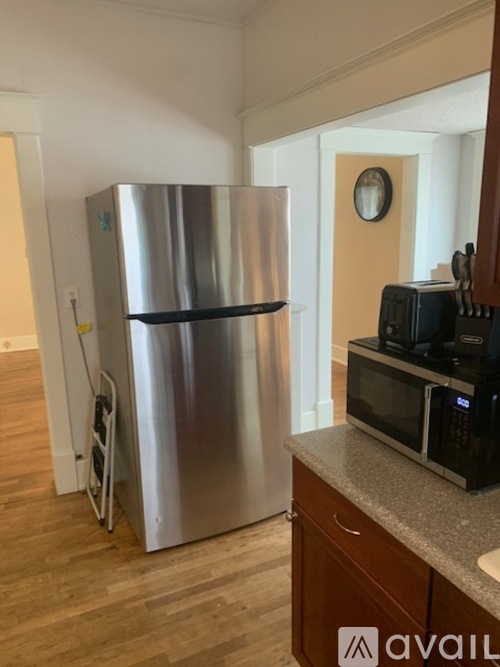 A stainless steel refrigerator is in a kitchen with a microwave on the counter.