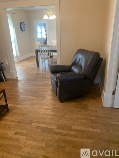 A black leather chair is in the foreground of a room with wooden flooring.