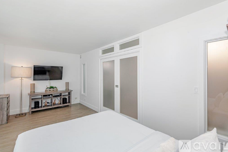 A bedroom with a large bed and a television on the wall.