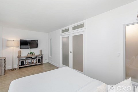 A bedroom with a large bed and a television on the wall.