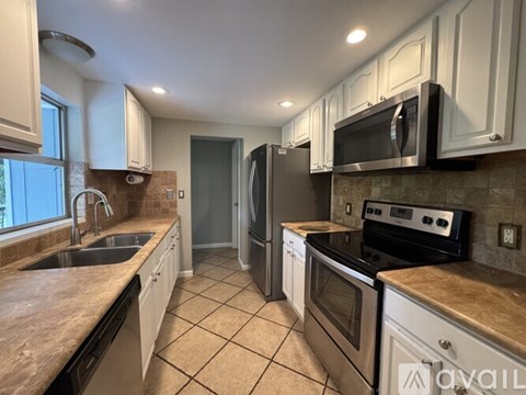 A kitchen with white cabinets and a tiled floor.