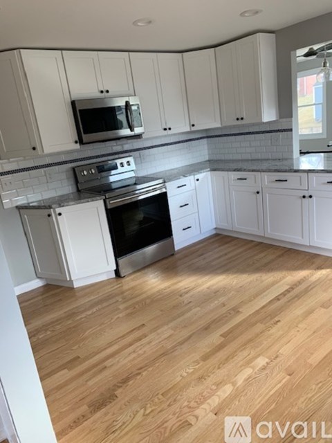 A kitchen with white cabinets and a wooden floor.
