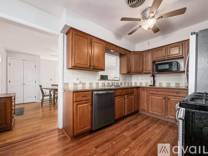 A kitchen with wooden cabinets and a black dishwasher.