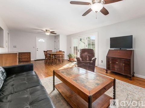 A living room with a black leather couch and a wooden coffee table.