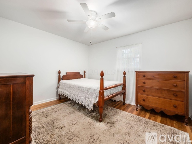 A bedroom with a bed, dresser, and rugs.