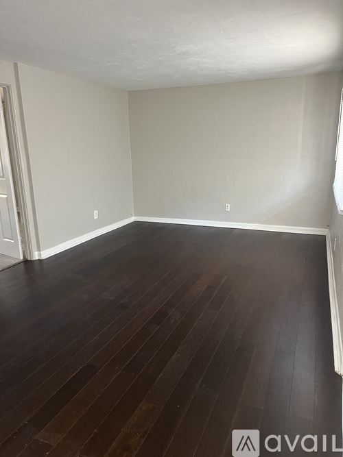 A room with wooden flooring and white walls.
