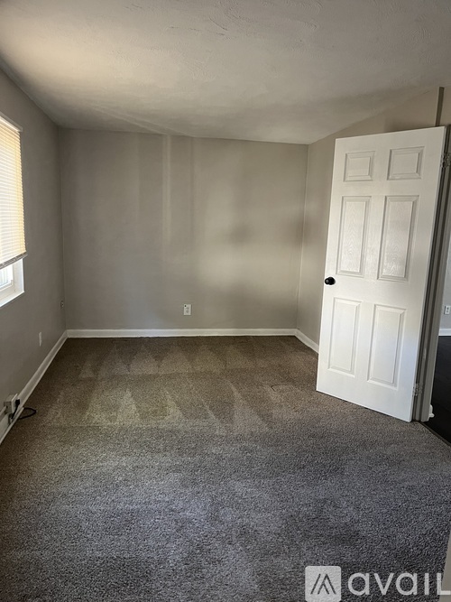 A room with a carpeted floor and a white door.