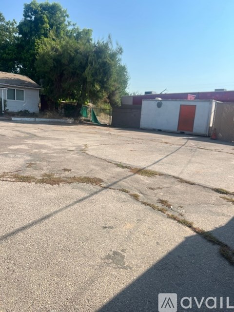 A parking lot with a white building and a red door in the background.