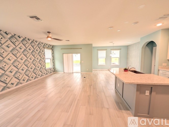 A spacious room with wooden flooring and a patterned wallpapered wall.