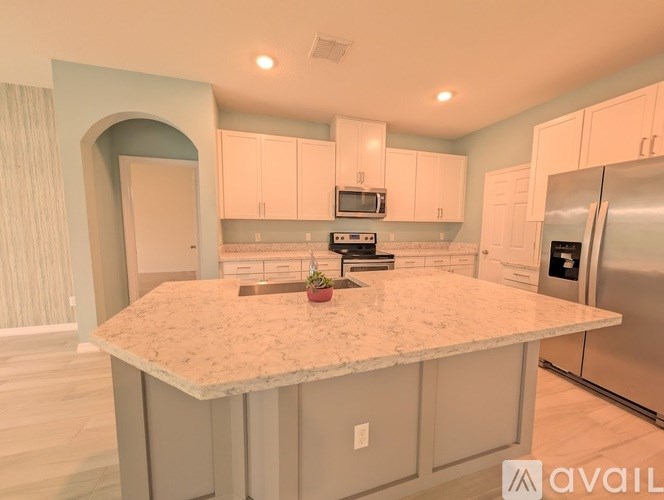 A kitchen with a marble countertop and stainless steel appliances.