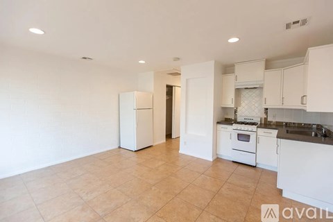 A kitchen with white appliances and cabinets is available for rent.