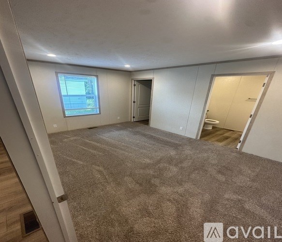 A spacious room with a carpeted floor and a window.