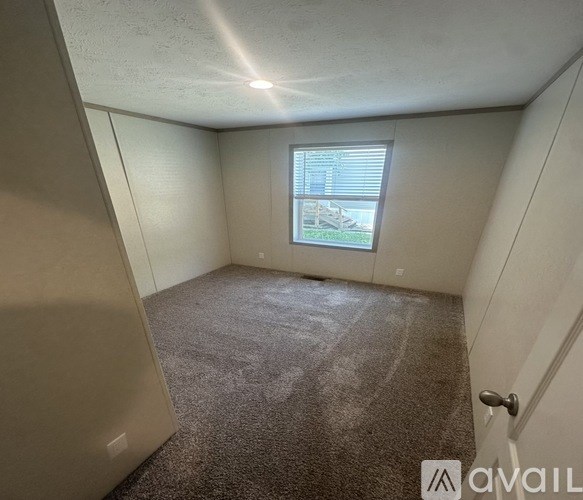 A room with a carpeted floor and a window with blinds.