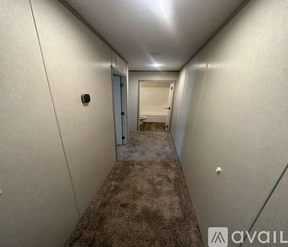 A long hallway with a carpeted floor and a door at the end.