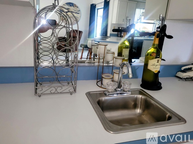 A kitchen with a sink and a bottle of wine.