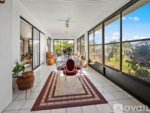 A living room with a red rug and a ceiling fan.