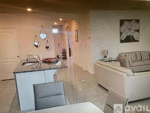A living room with a couch, chair, and a table with a lamp on it.