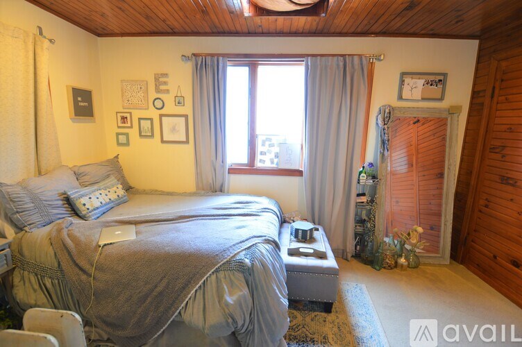 A bedroom with a large bed and a window with curtains.