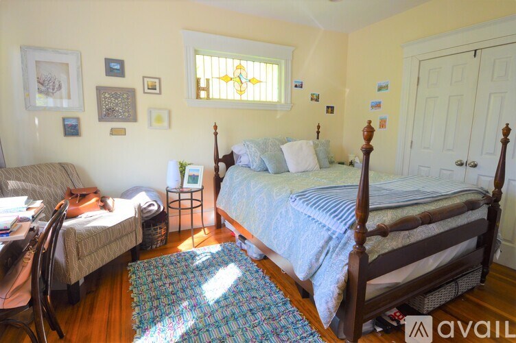 A bedroom with a bed, a chair, and pictures on the wall.