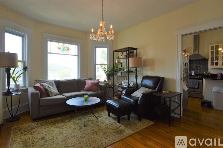 A living room with a grey couch, a black chair, and a glass chandelier.