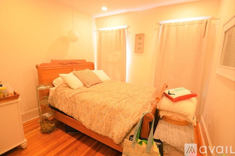 A bedroom with a bed, nightstand, and window with curtains.