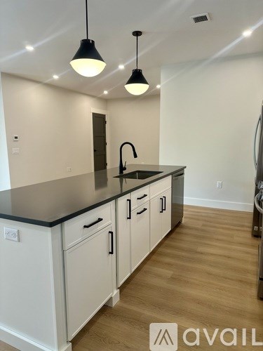 A kitchen with white cabinets and a black countertop.