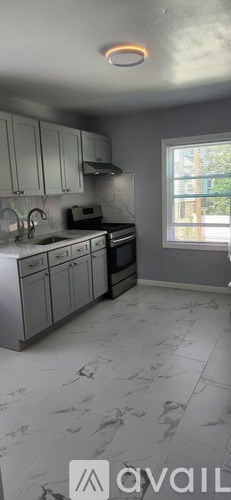 A kitchen with white cabinets and a window.