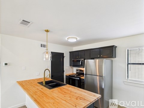 A kitchen with a wooden counter top and stainless steel appliances.