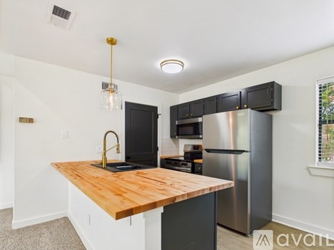 A kitchen with a wooden counter top and stainless steel appliances.