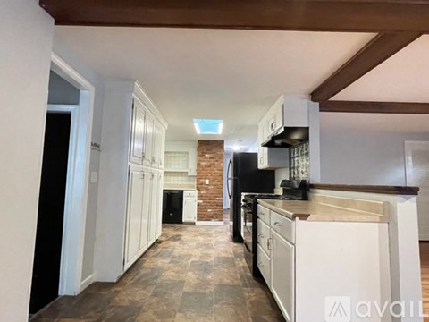 A kitchen with white cabinets and a brick wall.